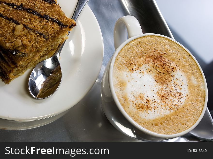 Cappuccino in a white cup with honey cake