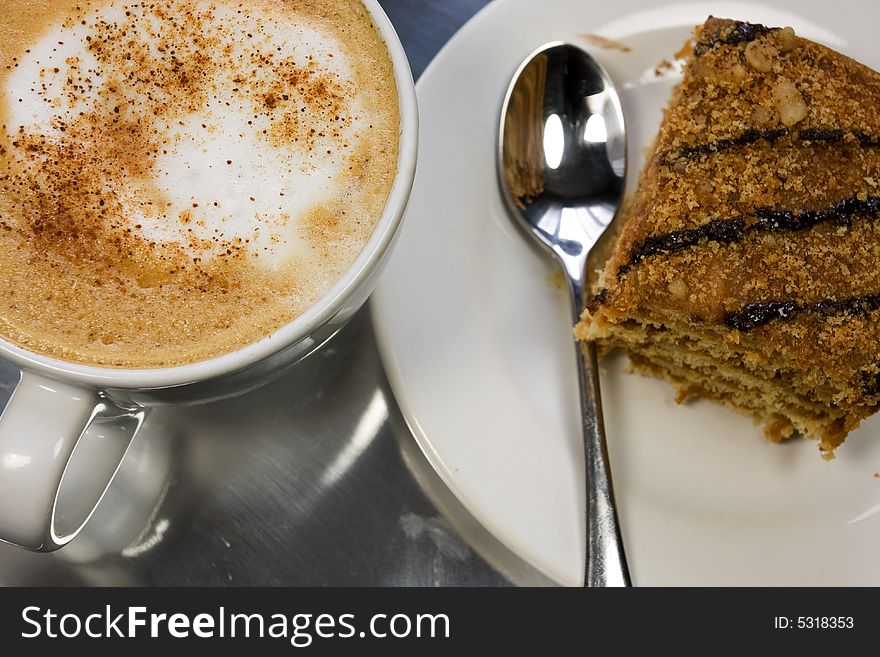 Cappuccino in a white cup with honey cake