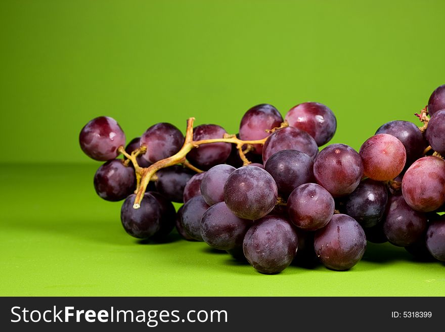 The bunch of ripe red grapes on the green background