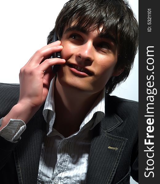 A portrait about a trendy attractive guy who is smiling and he is ringing up somebody. He is wearing a white shirt and a stylish black suit. A portrait about a trendy attractive guy who is smiling and he is ringing up somebody. He is wearing a white shirt and a stylish black suit.