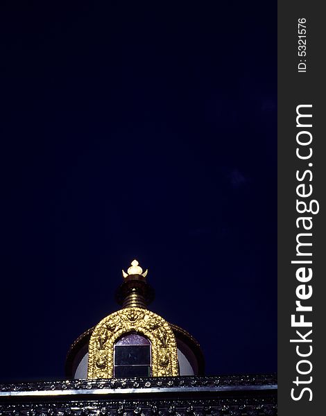 Shining top part of a huge golden pagoda with wonderful craftsmanship in pure dark background