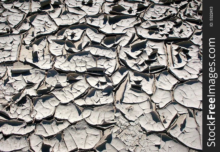 Closeup of dried out river bed, curled sheets of gray clay