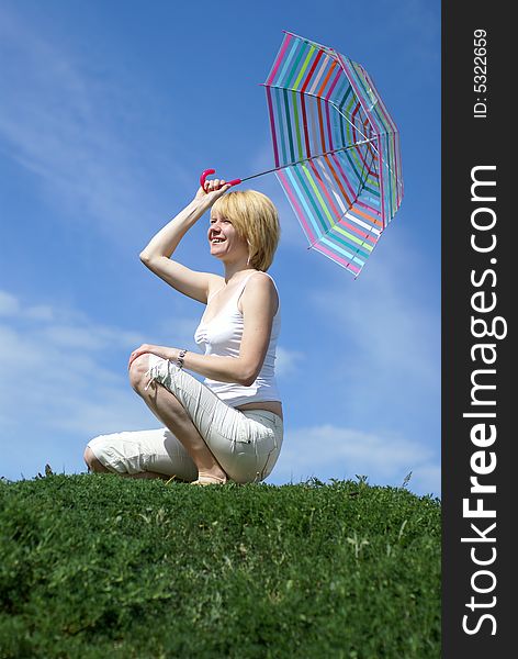 Yong charming girl sitting on the meadow with umbrella. Yong charming girl sitting on the meadow with umbrella