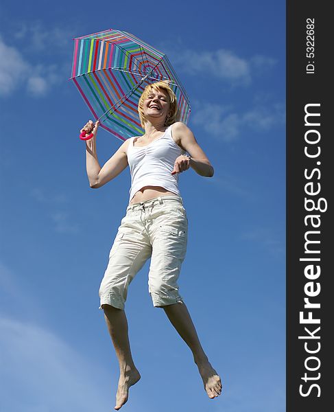 Yong charming girl jumping with umbrella against blue sky