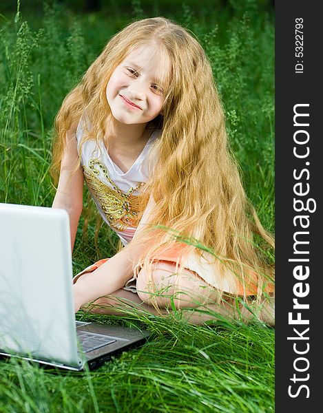 Funny little girl sitting with laptop in green grass. Funny little girl sitting with laptop in green grass