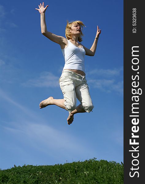 Happy woman jump in field under blue sky and clouds