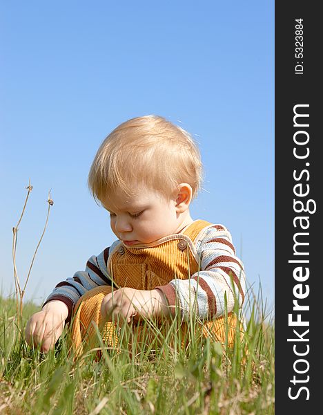 The child sits in green grass