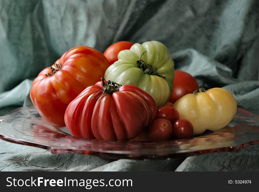 Mixture of heirloom and common tomatoes arranged on heirloom pink glass plate. Mixture of heirloom and common tomatoes arranged on heirloom pink glass plate.