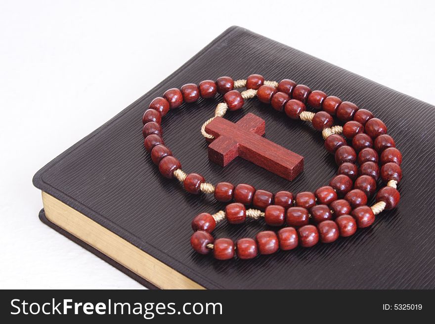 Rosary over a religious book with white background