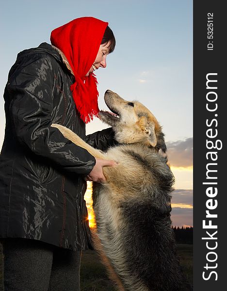 The woman stands with a dog. The woman stands with a dog