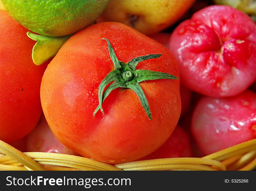 This is the closed-up picture of fresh colorful, energy and  vitamins full fruits with the water drops  . The red tomato is on the central part of picture . . This is the closed-up picture of fresh colorful, energy and  vitamins full fruits with the water drops  . The red tomato is on the central part of picture .