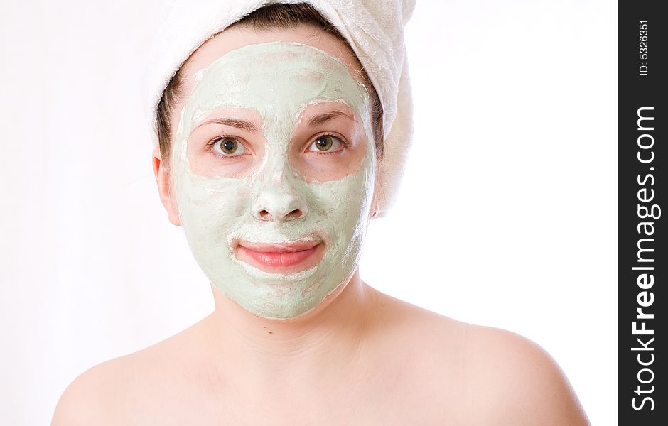 Young woman with green mask on her face healthy treatment, white towel