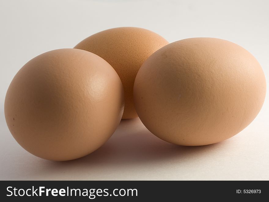 Three large chicken eggs of brown color on a white background.