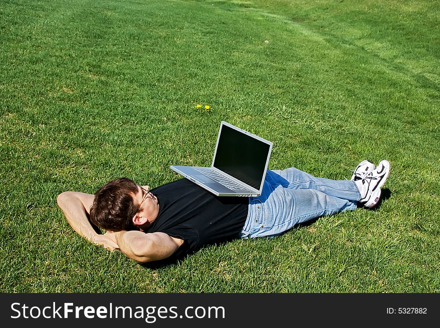 Man lying on the grass with laptop. Man lying on the grass with laptop