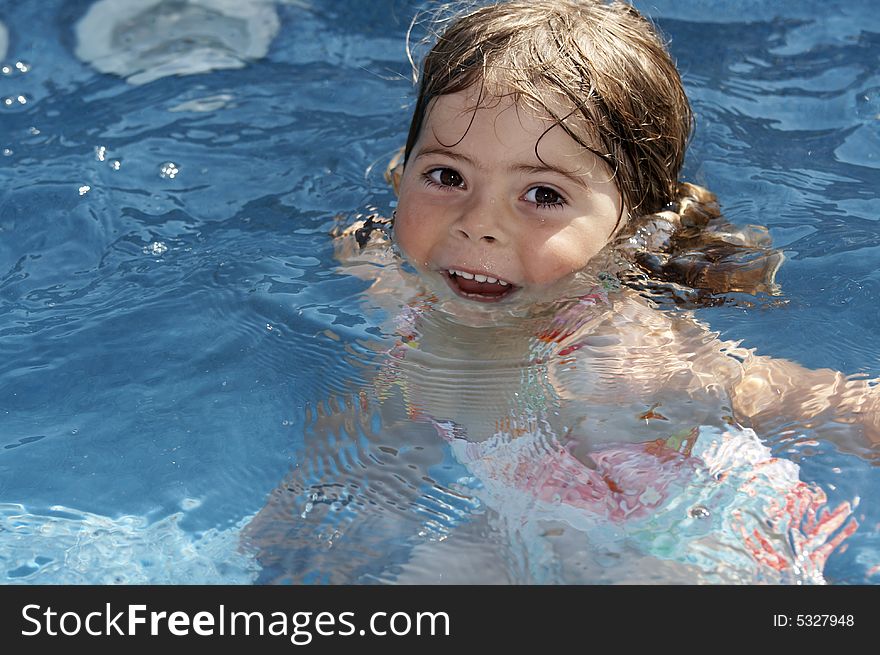 A cute little girl looking at pool water during the summer. A cute little girl looking at pool water during the summer