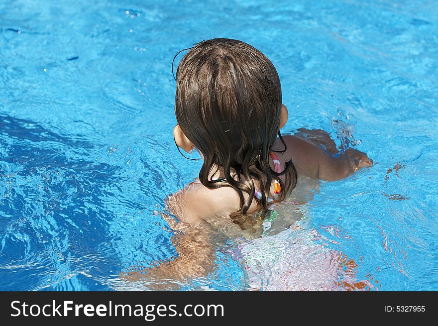 A cute little girl looking at pool water during the summer. A cute little girl looking at pool water during the summer