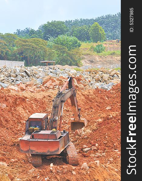 A red tractor busy with excavation work at a construction site. A red tractor busy with excavation work at a construction site