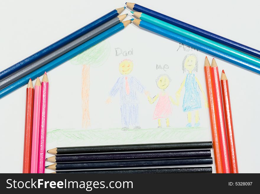 Multicolored pencils at a white paper with a child's family picture. Multicolored pencils at a white paper with a child's family picture