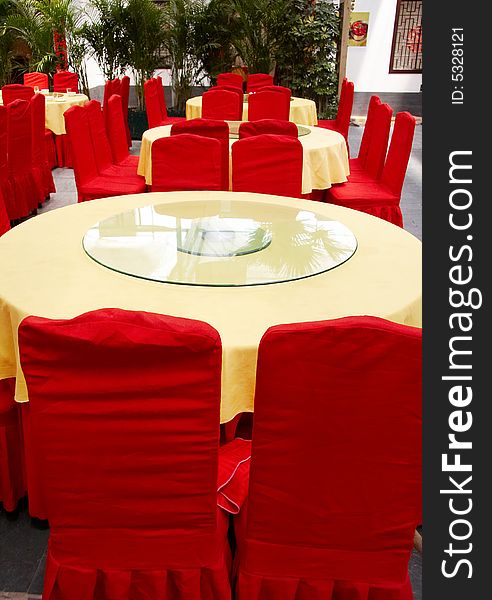 Interior of chinese restaurant with round tables and red chairs.