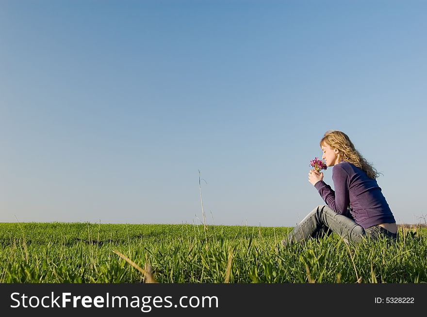 Girl sits on a grass and smells a bunch of flowers. Girl sits on a grass and smells a bunch of flowers