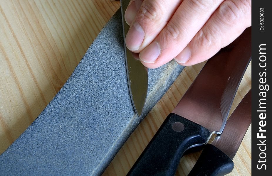 Gray whetstone and kitchen knives on wooden background. Gray whetstone and kitchen knives on wooden background