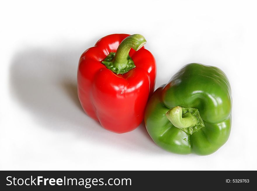 A fresh and tasty red and green pepper reflected on white backround.