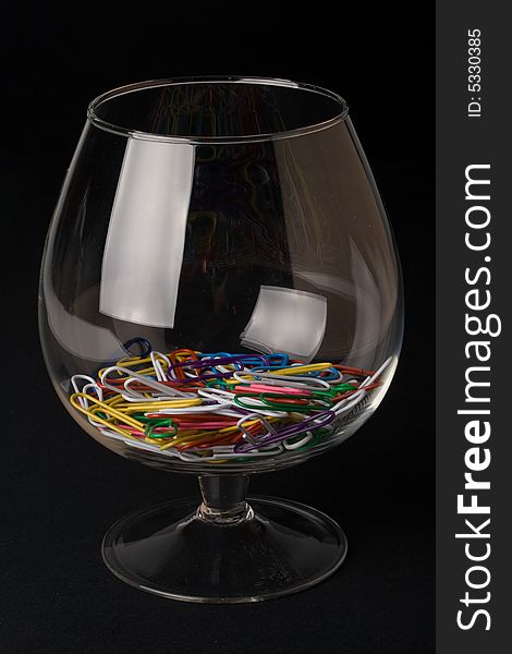 Colored paperclips in a glass on a black background. Close up. Selective focus.