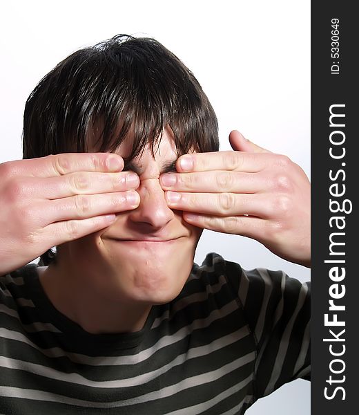 A portrait about a trendy attractive guy who is hiding his eyes with two hands. He is wearing a striped t-shirt. A portrait about a trendy attractive guy who is hiding his eyes with two hands. He is wearing a striped t-shirt.