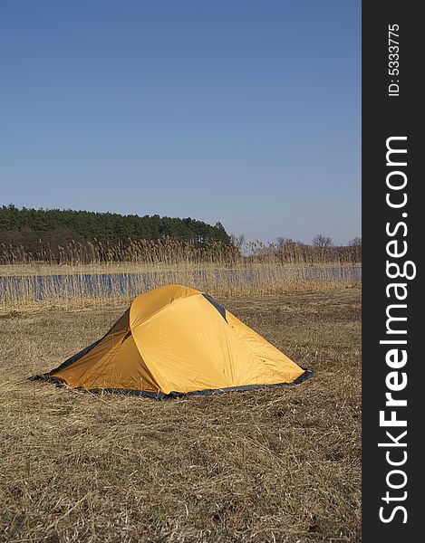 Orange tent on the shore of the lake