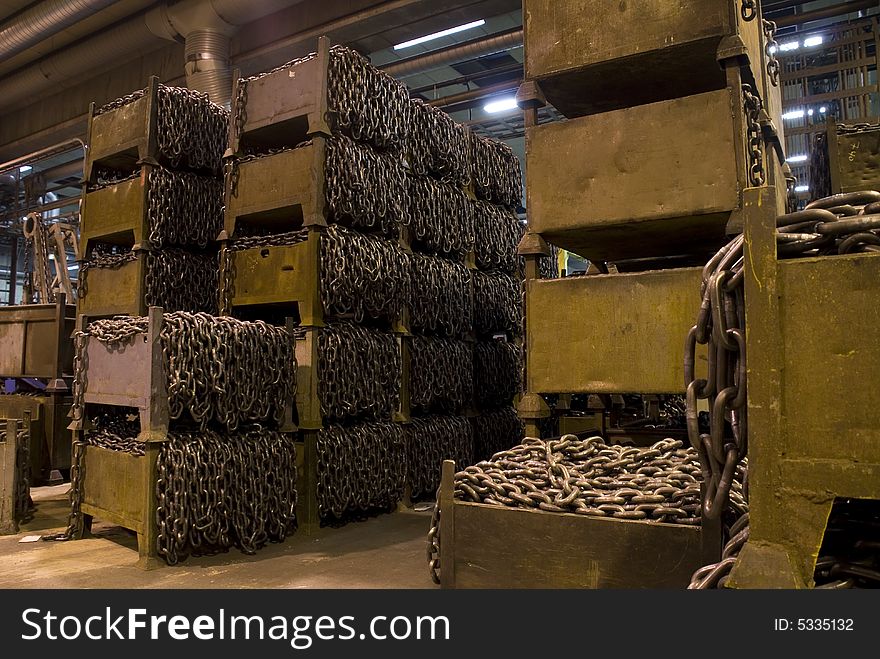 Many boxes with chains, inside a chain factory.