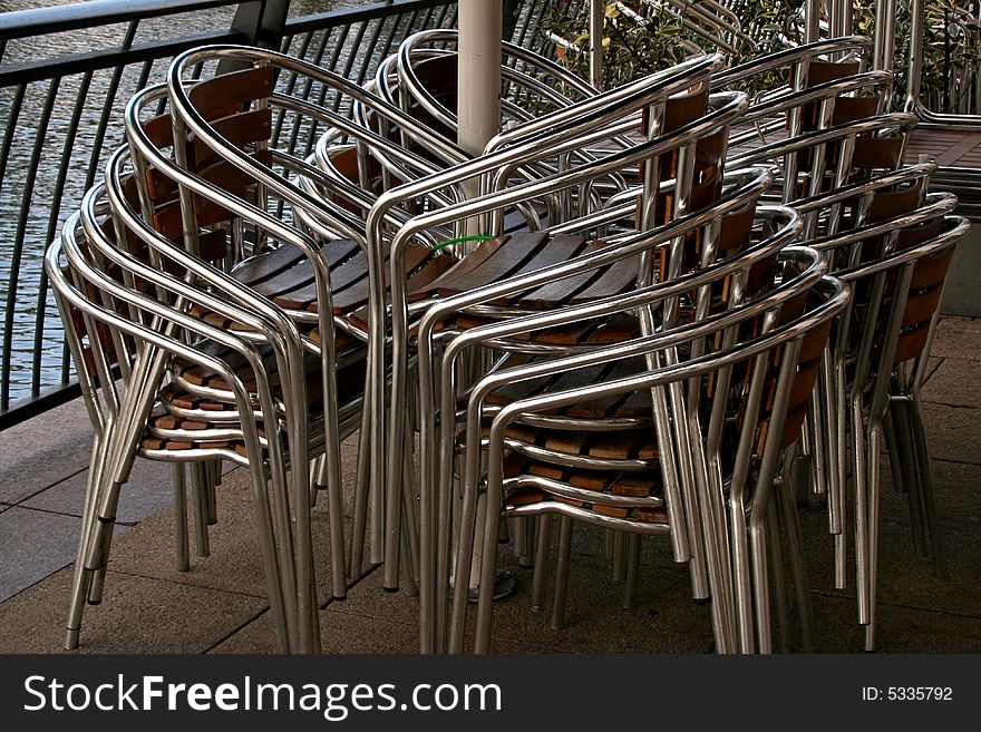 Stacked bar chairs outside next to water