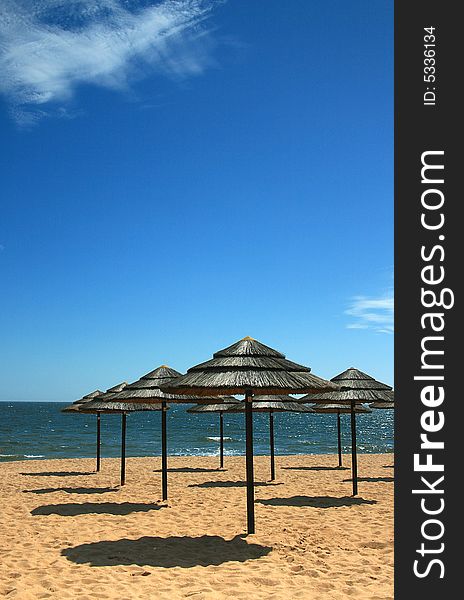 Straw beach parasols against a blue sky. Straw beach parasols against a blue sky