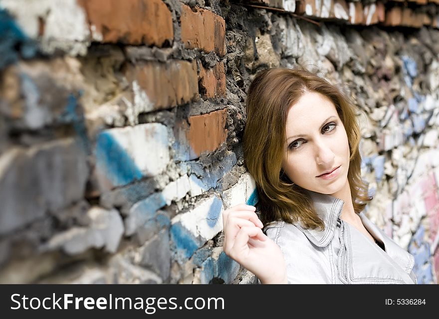 Close-up of an attractive young woman leaning against a graffiti painted wall. Close-up of an attractive young woman leaning against a graffiti painted wall