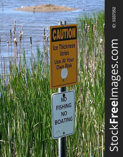 Two warning signs posted overlooking a marsh area. Two warning signs posted overlooking a marsh area