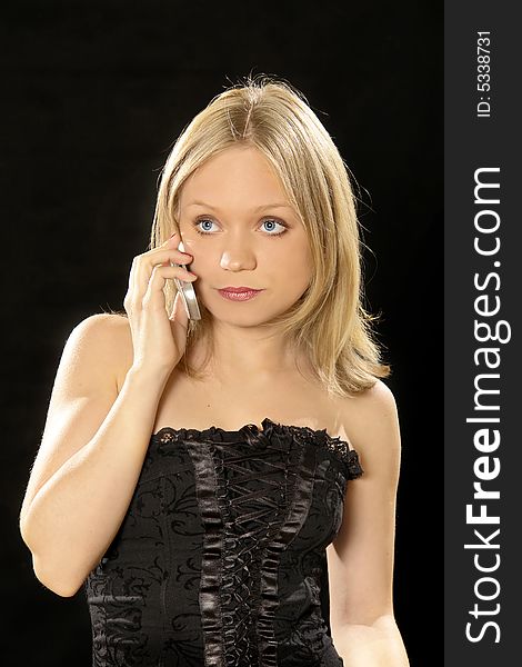 Portrait of a beautiful girl with a cell phone isolated on black background. Portrait of a beautiful girl with a cell phone isolated on black background