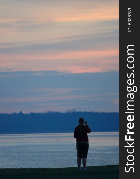 Soft Focus sillhouette of a person in quiet contemplation on the shore of a lake at Sunset. Soft Focus sillhouette of a person in quiet contemplation on the shore of a lake at Sunset