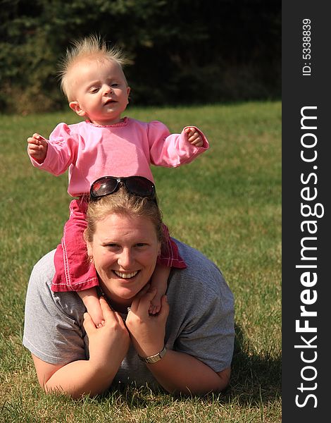 A young mother enjoying a summer day at the park with her young daughter. A young mother enjoying a summer day at the park with her young daughter