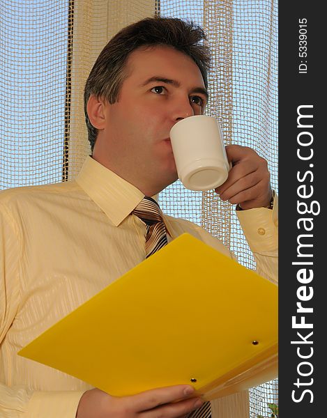 Man in a tie on a background a window with a white cup. Man in a tie on a background a window with a white cup