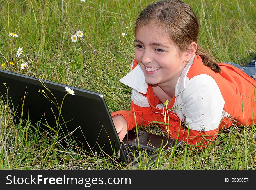 Girl lies on a grass on to the meadow and works with a notebook. Girl lies on a grass on to the meadow and works with a notebook