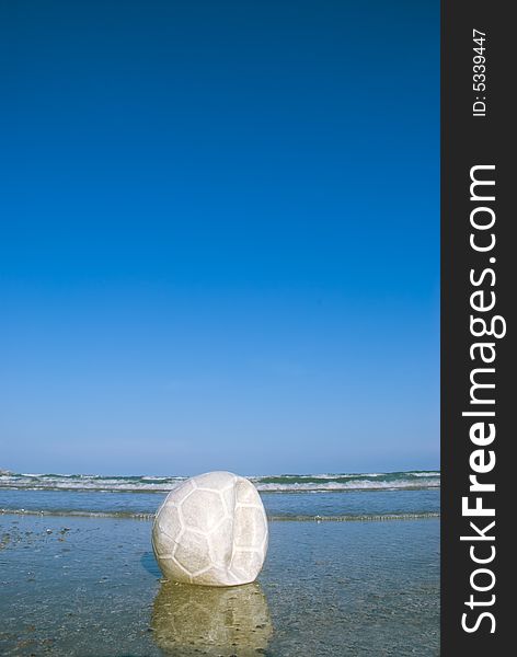 A deflated white soccer ball on a beach. A deflated white soccer ball on a beach
