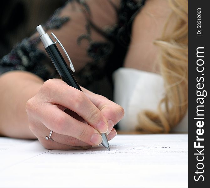 Bride signing the marriage certificate after the wedding. Bride signing the marriage certificate after the wedding