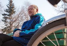 Eldely Man Sitting On A Bench Near His Bicycle In A City Park Royalty Free Stock Photo
