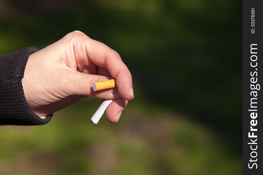 Female hand breaks a cigarette closeup outside