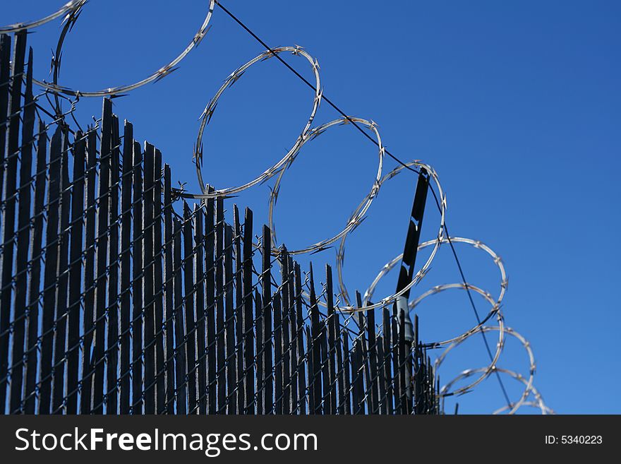 A worms eye view of a barbed wire fence in front of a blue sky.