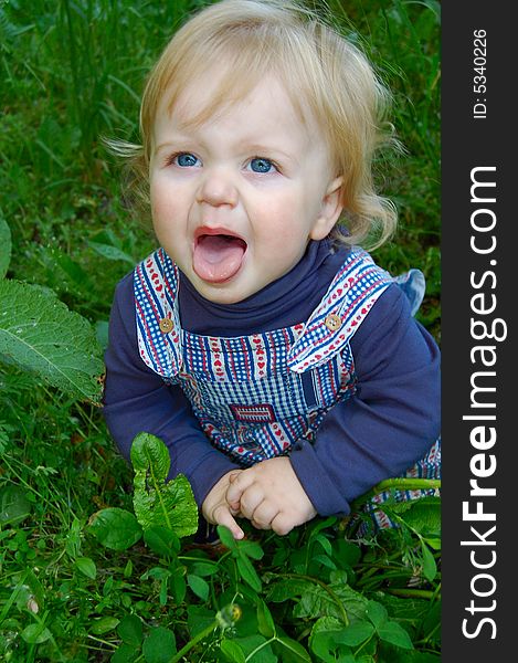 Sweet baby boy sitting in grass with his tounge out. Sweet baby boy sitting in grass with his tounge out