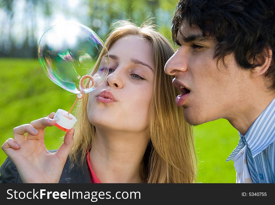 Attractive multi-racial couple in love blowing bubbles on nature