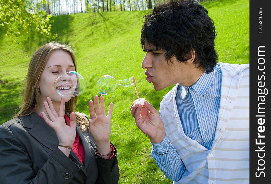 Attractive multi-racial couple in love blowing bubbles on nature