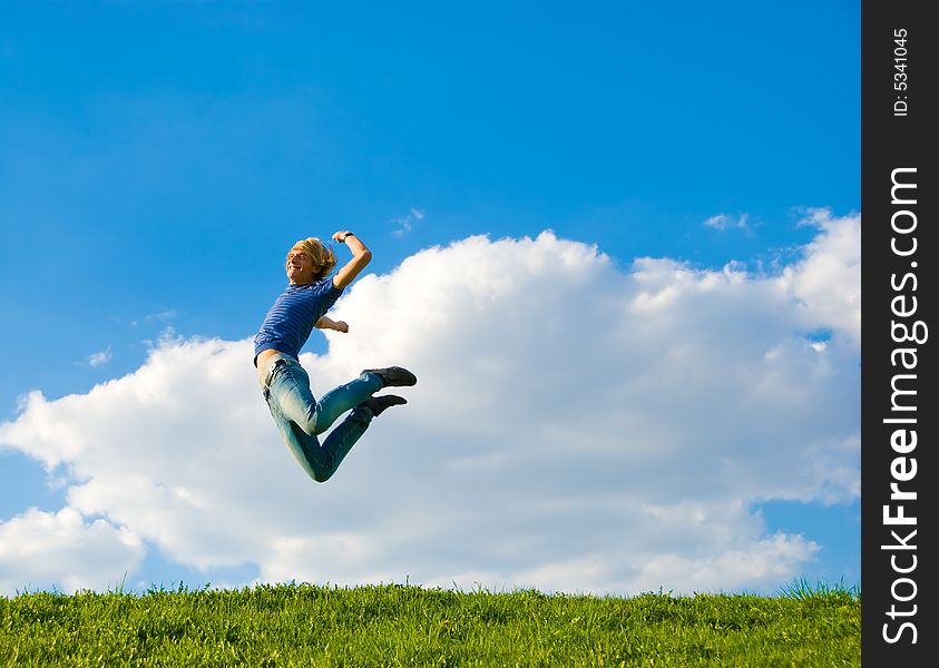 Happy teenager jumping over green grass field.