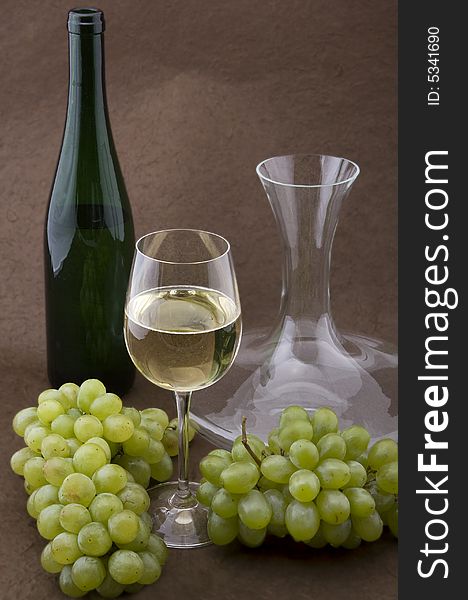 White wine with bottle, glasses and grapes against a background