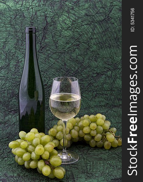 White wine with bottle, glasses and grapes against a background